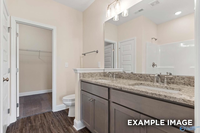 bathroom featuring hardwood / wood-style floors, vanity, toilet, and walk in shower