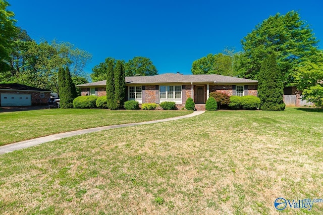 single story home featuring a garage, a front lawn, and brick siding