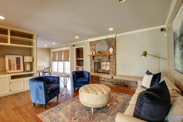 living area featuring a brick fireplace, ornamental molding, wood finished floors, and recessed lighting