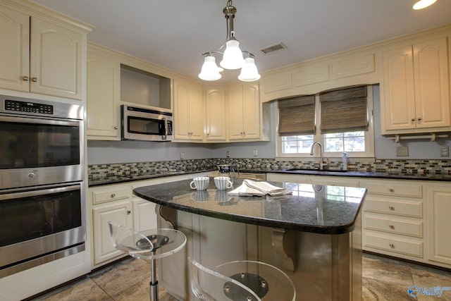 kitchen with stainless steel appliances, hanging light fixtures, backsplash, a sink, and a kitchen bar