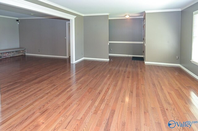 spare room featuring baseboards, crown molding, and wood finished floors