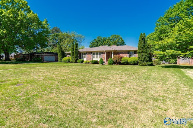 ranch-style house featuring a garage, brick siding, and a front yard