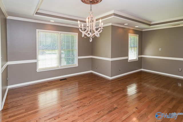 spare room with wood finished floors, a raised ceiling, visible vents, and baseboards