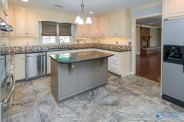 kitchen featuring a kitchen island, a sink, visible vents, appliances with stainless steel finishes, and crown molding