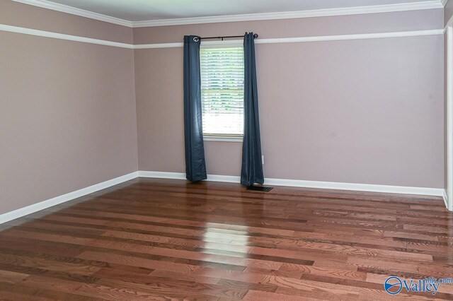 empty room with baseboards, visible vents, ornamental molding, and wood finished floors