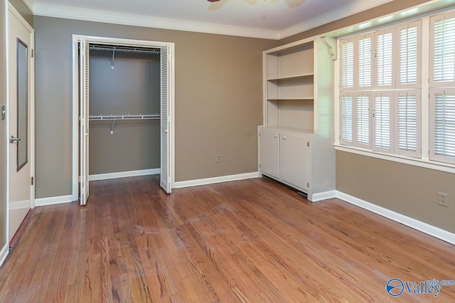 unfurnished bedroom with ornamental molding, a closet, baseboards, and wood finished floors