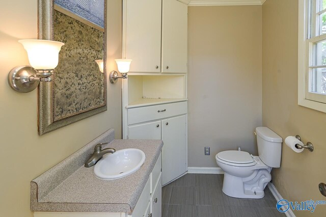 half bath with toilet, baseboards, and vanity