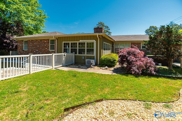 ranch-style home with brick siding, fence, a chimney, and a front lawn