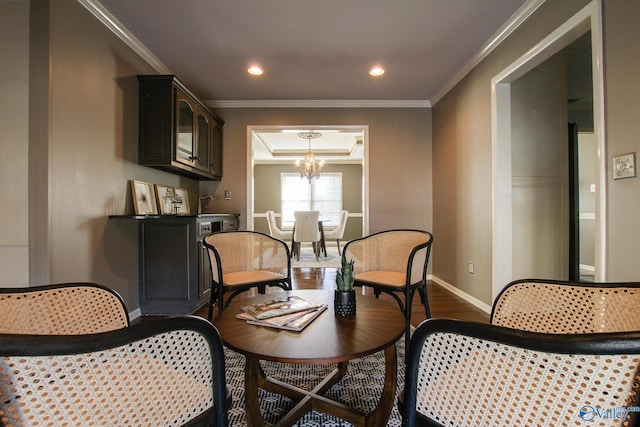 sitting room featuring a tray ceiling, ornamental molding, dark wood-type flooring, a chandelier, and baseboards