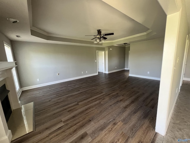 unfurnished living room featuring dark hardwood / wood-style floors, a raised ceiling, ceiling fan, and crown molding