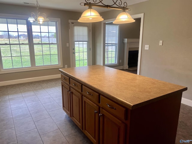 kitchen with a notable chandelier, a center island, light tile patterned floors, and hanging light fixtures