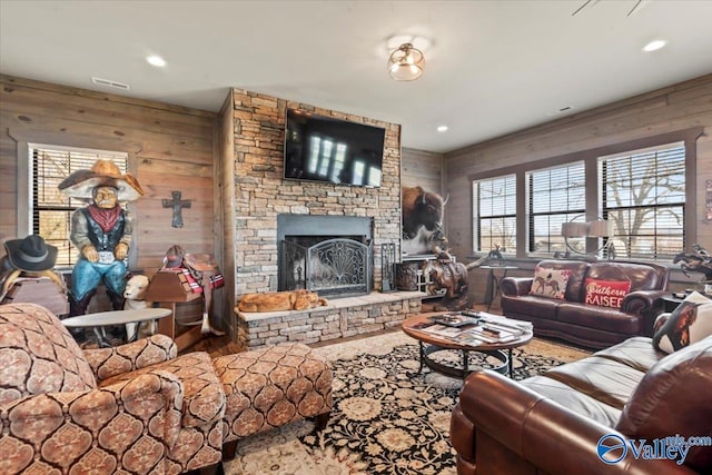 living room with recessed lighting, a brick fireplace, visible vents, and wooden walls