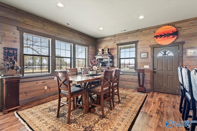 dining area with wood walls, wood finished floors, visible vents, and recessed lighting