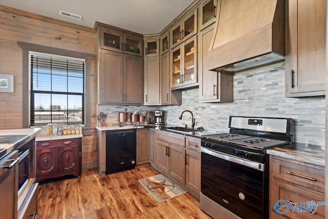 kitchen featuring black dishwasher, custom exhaust hood, visible vents, stainless steel gas stove, and a sink