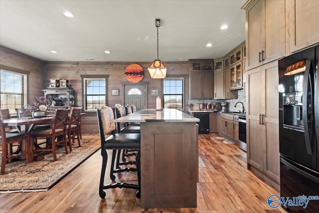 kitchen with light wood-type flooring, a center island, black appliances, and a breakfast bar area