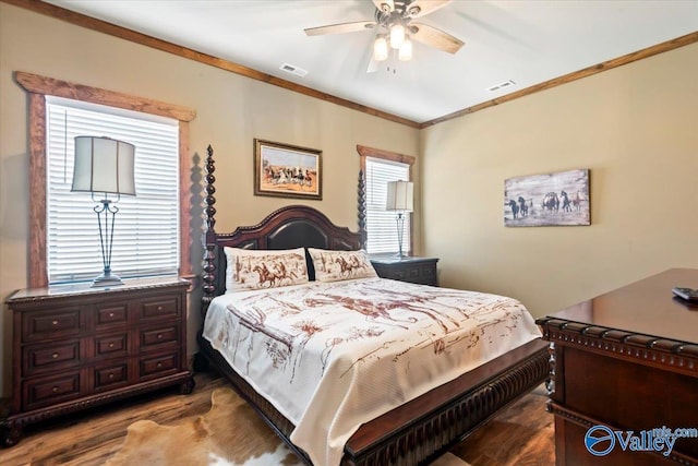 bedroom with crown molding, visible vents, ceiling fan, and wood finished floors