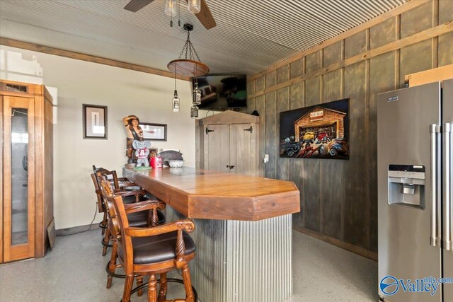 bar with a dry bar, stainless steel fridge, a ceiling fan, and wooden walls