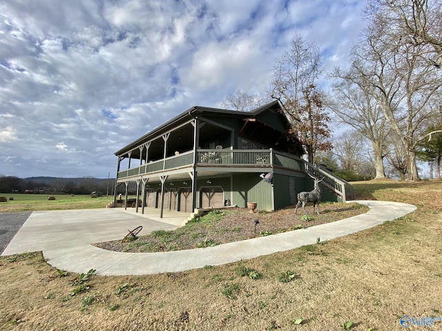 view of front of home with a front yard, a carport, driveway, a wooden deck, and stairs