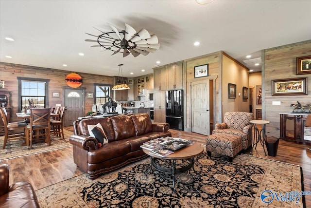 living area featuring wood walls, ceiling fan, wood finished floors, and recessed lighting