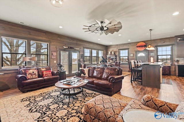 living area featuring wooden walls, wood finished floors, and french doors