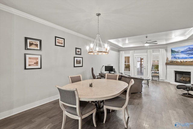 dining room featuring ceiling fan with notable chandelier, dark hardwood / wood-style flooring, a raised ceiling, and ornamental molding