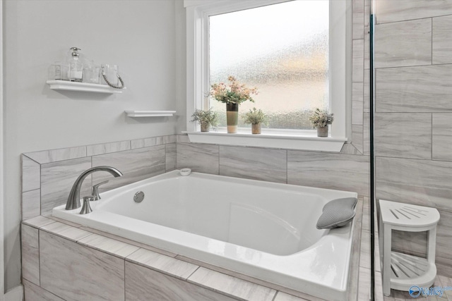 bathroom with tiled bath and a healthy amount of sunlight