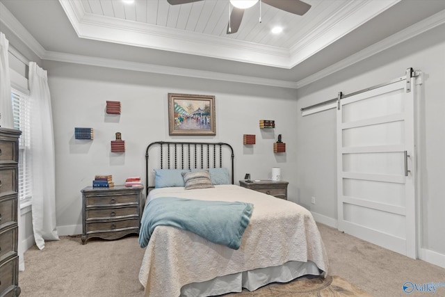 carpeted bedroom with a barn door, a tray ceiling, ceiling fan, and ornamental molding