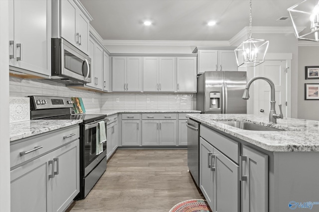 kitchen with appliances with stainless steel finishes, gray cabinets, hanging light fixtures, and crown molding