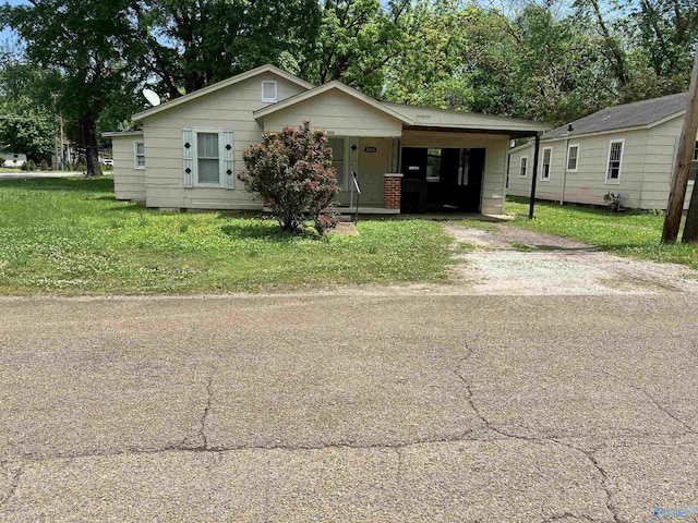 bungalow with dirt driveway, a carport, and a front yard