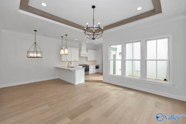 unfurnished living room with sink, light hardwood / wood-style flooring, a notable chandelier, and a tray ceiling