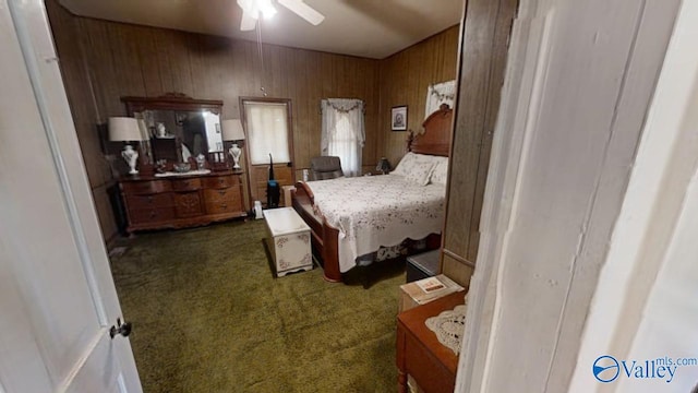 carpeted bedroom featuring ceiling fan and wood walls