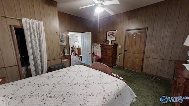 carpeted bedroom featuring ceiling fan and wooden walls