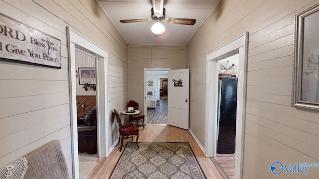 hall with wood walls and light wood-type flooring