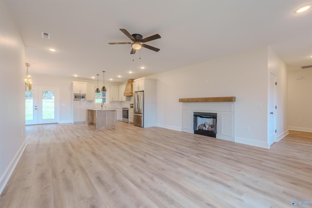 unfurnished living room with light hardwood / wood-style flooring, ceiling fan, and sink