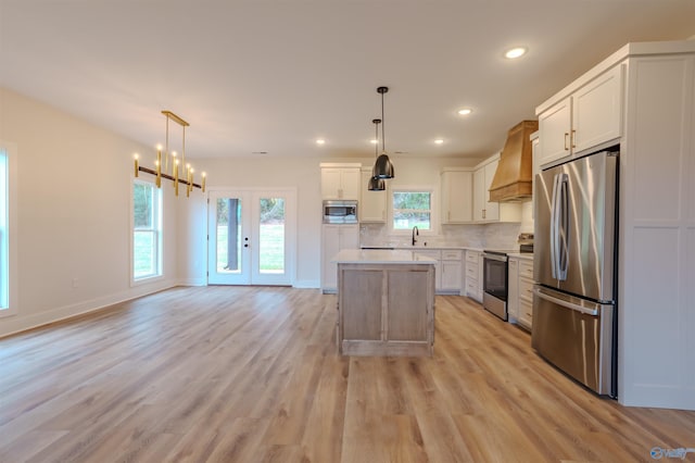 kitchen with a center island, light hardwood / wood-style floors, stainless steel appliances, and hanging light fixtures