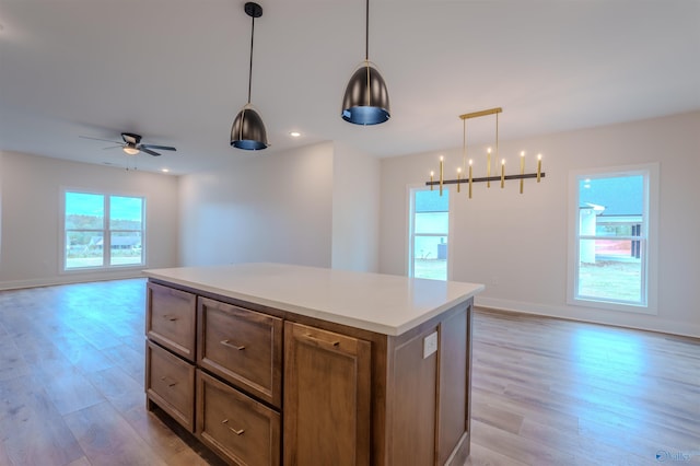 kitchen with ceiling fan with notable chandelier, decorative light fixtures, light wood-type flooring, and a center island