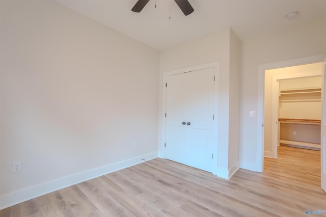 unfurnished bedroom featuring ceiling fan, light hardwood / wood-style floors, and a closet