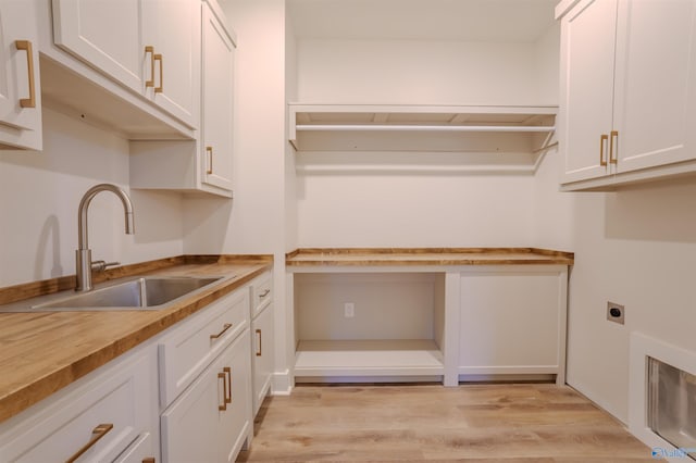 laundry room with hookup for an electric dryer, sink, cabinets, and light wood-type flooring