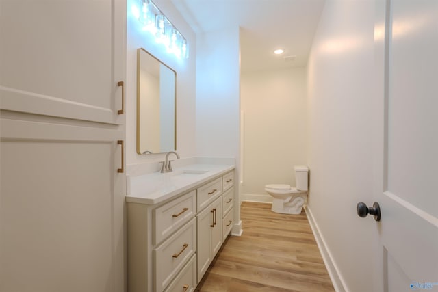 bathroom with hardwood / wood-style flooring, vanity, and toilet