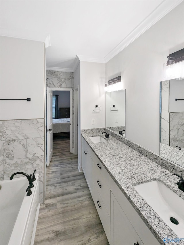 bathroom featuring crown molding, tile walls, hardwood / wood-style floors, vanity, and a bathing tub