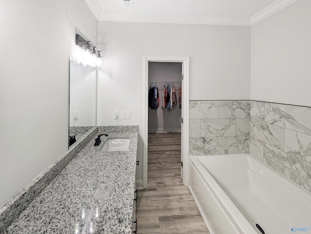 bathroom with crown molding, a tub to relax in, vanity, and wood-type flooring