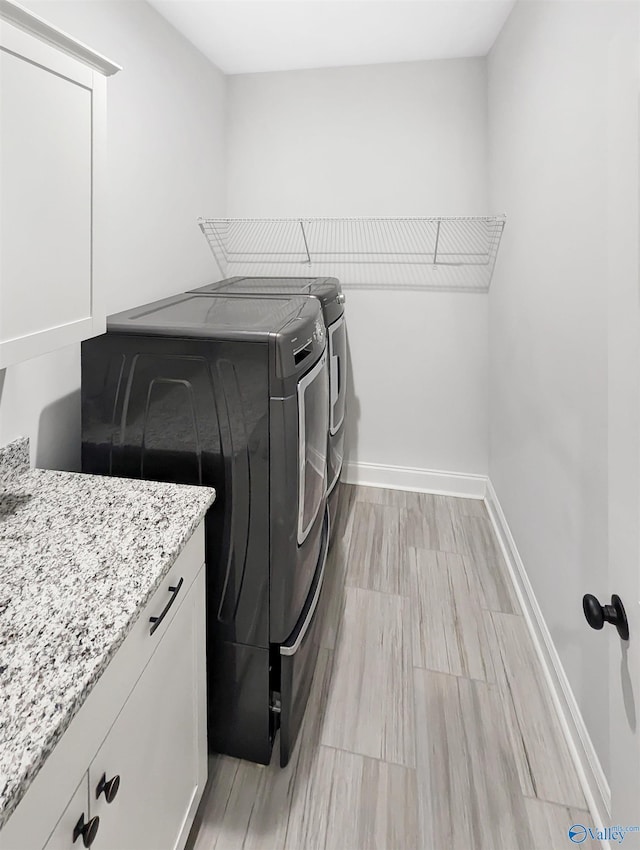 laundry room with cabinets, washer and dryer, and light wood-type flooring