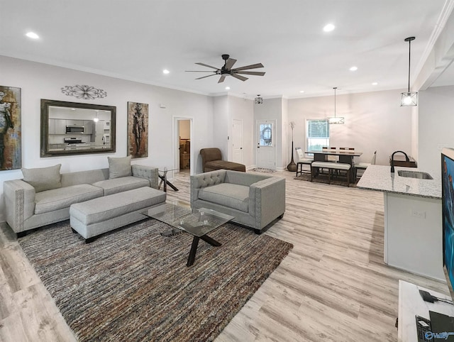 living room featuring crown molding, ceiling fan, light hardwood / wood-style floors, and sink