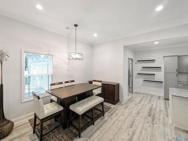 dining space with ornamental molding, an inviting chandelier, and light hardwood / wood-style flooring