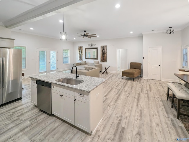 kitchen featuring sink, appliances with stainless steel finishes, a kitchen island with sink, hanging light fixtures, and light stone countertops