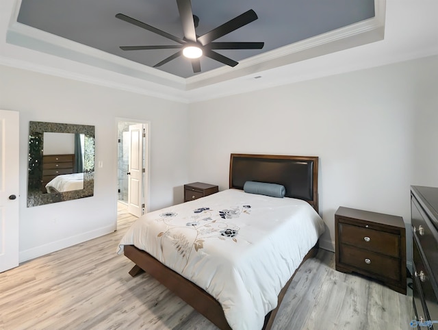 bedroom with a raised ceiling, light hardwood / wood-style flooring, ceiling fan, and ensuite bath