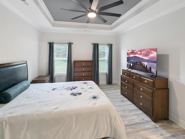 bedroom with a raised ceiling, ornamental molding, ceiling fan, and light hardwood / wood-style flooring