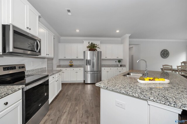 kitchen with stainless steel appliances, sink, hardwood / wood-style flooring, a center island with sink, and white cabinets