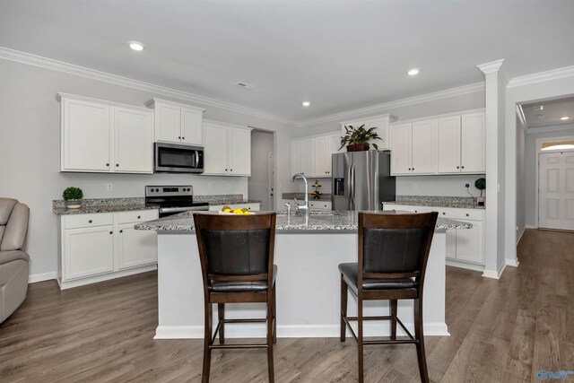 kitchen with white cabinetry, a kitchen bar, stainless steel appliances, an island with sink, and dark hardwood / wood-style floors