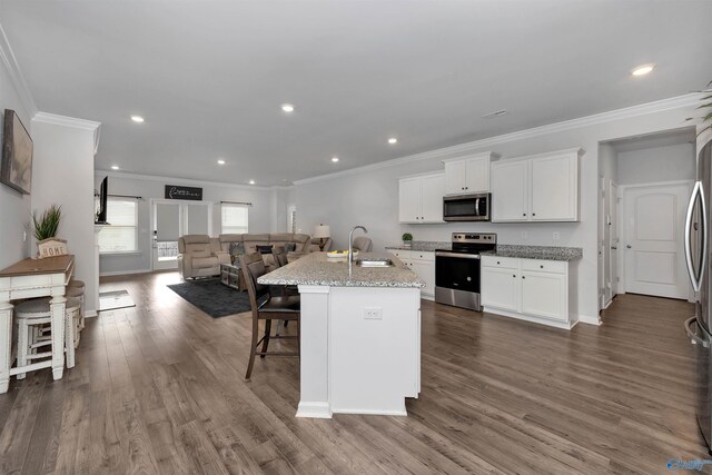 kitchen featuring dark hardwood / wood-style floors, a center island with sink, appliances with stainless steel finishes, sink, and light stone counters